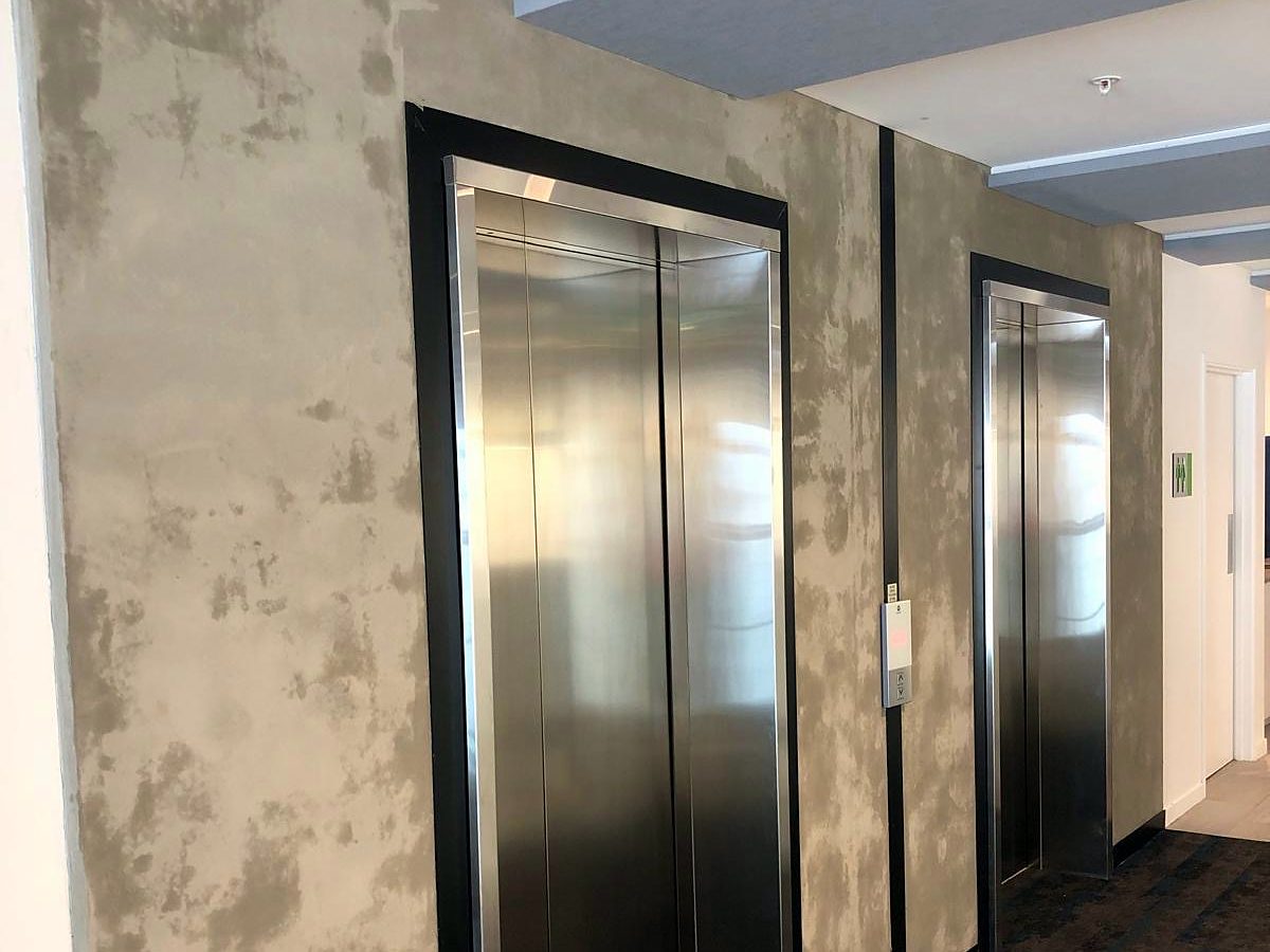 Close view of the hand-applied concrete-look finish beside the lifts