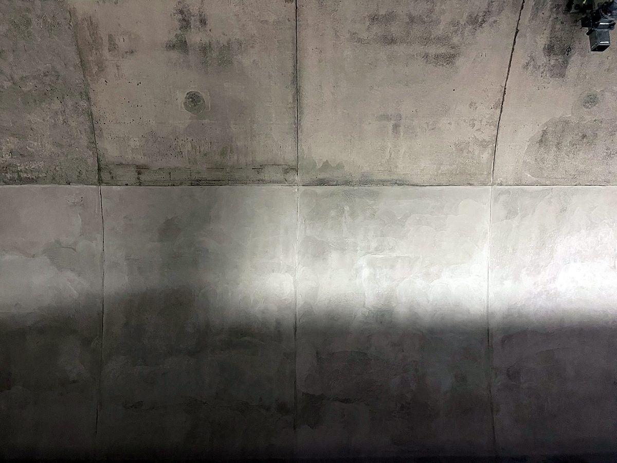 Tunnel wall showing untreated concrete above and resurfaced concrete below
