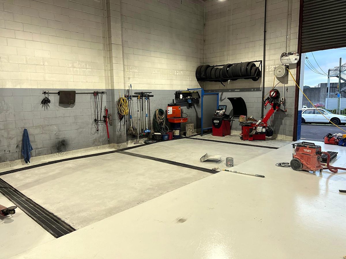 Workshop floor part-way through coating, bare concrete beside finished coating