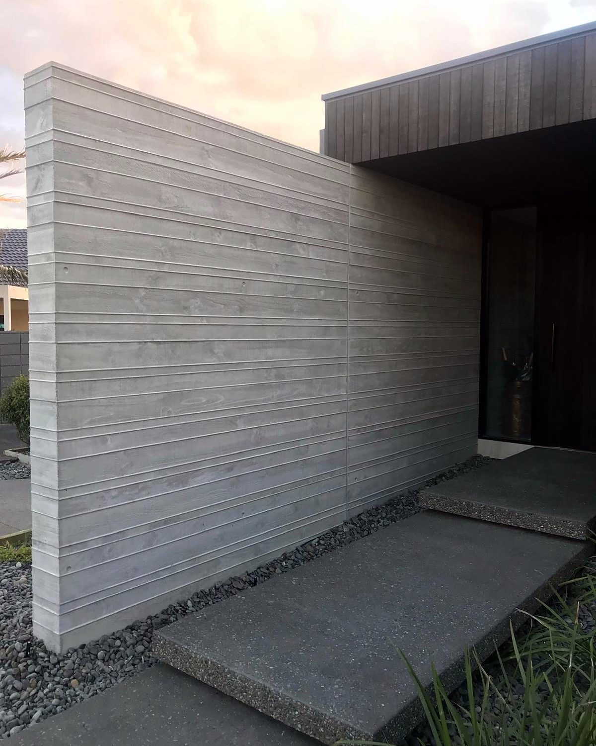 Board-formed concrete entry wall at dusk, Mount Maunganui residence