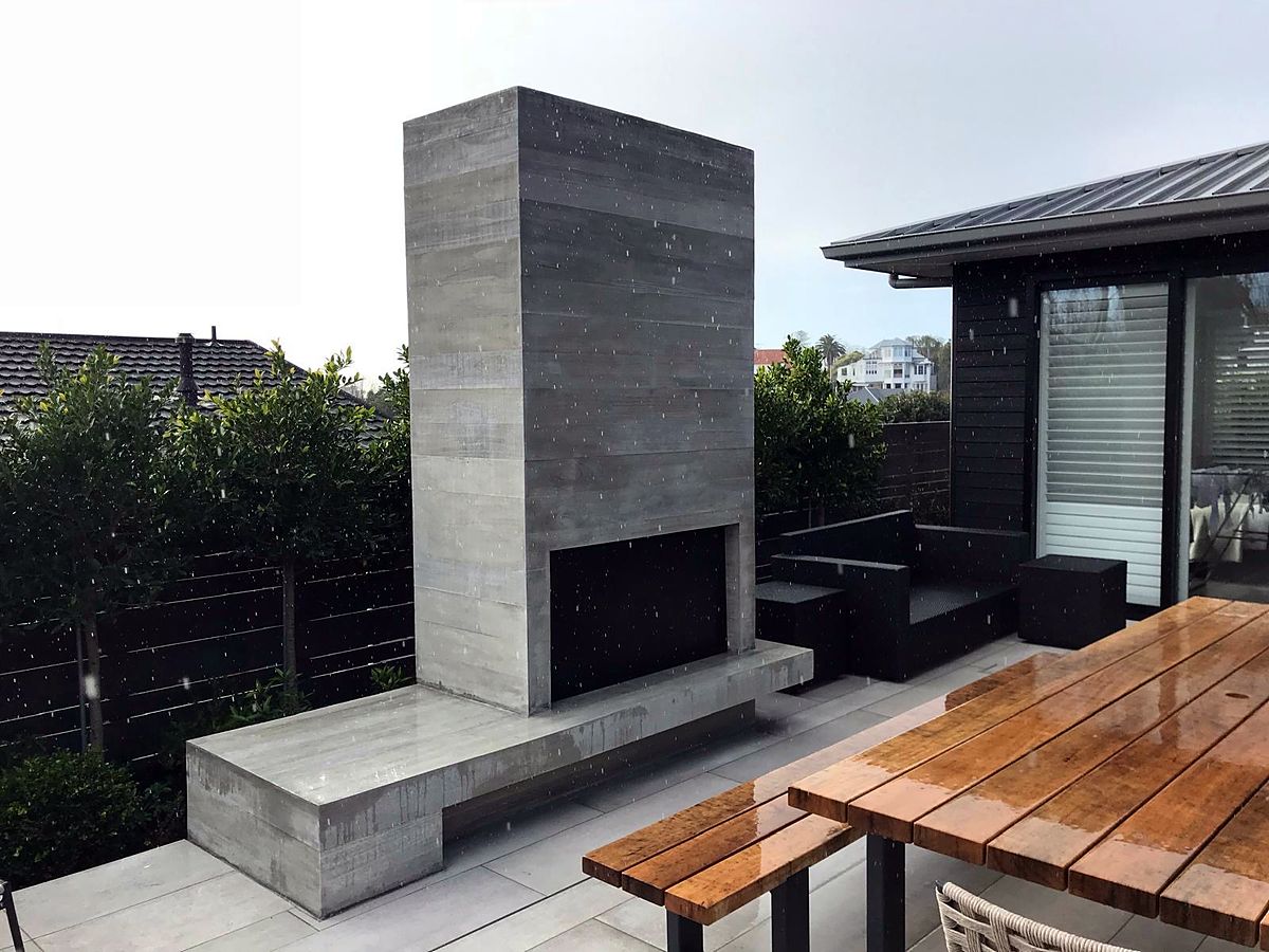 Board-formed concrete outdoor fireplace and bench on a patio